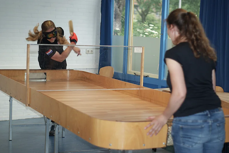 Twee showdownspelers in actie aan de showdowntafel terwijl een van hen uithaalt met het batje.