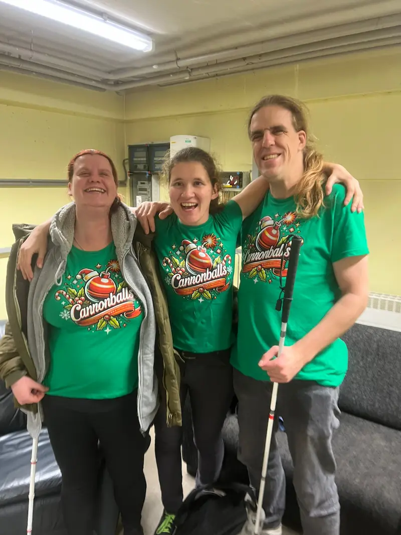 Drie lachende Cannonballs-leden staan arm in arm in hun groene kerstshirts voor het kersttoernooi van showdownvereniging ZTTV Zeist.